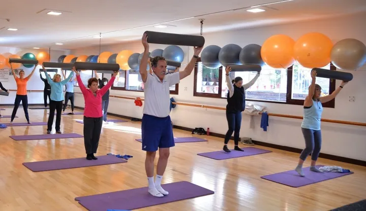Clase grupal de gimnasia con implementos en la sala de entrenamiento del Club