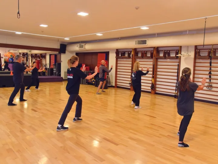 Grupo de socios practicando movimientos de Tai Chi en una sala del Club
