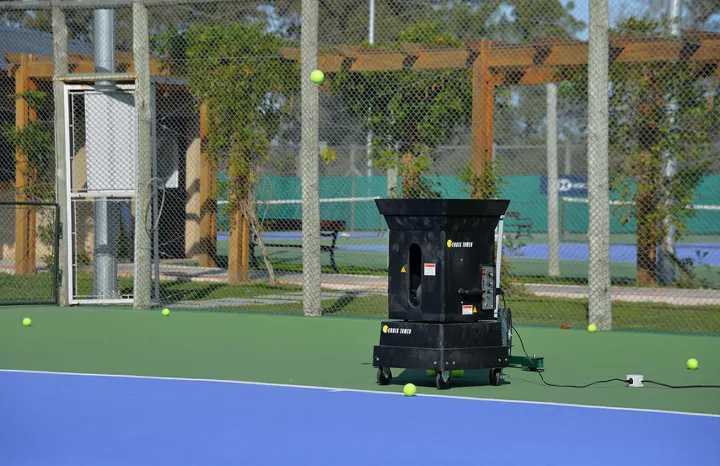 Máquina lanza pelotas en funcionamiento sobre una cancha de tenis de la Sede Solymar