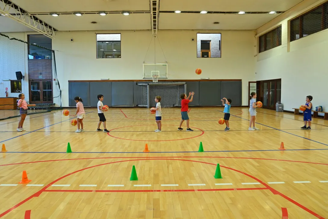 Niños practicando lanzamientos y manejo de pelota durante una clase de básquetbol