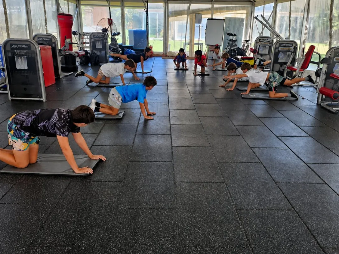 Niños realizando ejercicios en estaciones durante una clase de Circuito