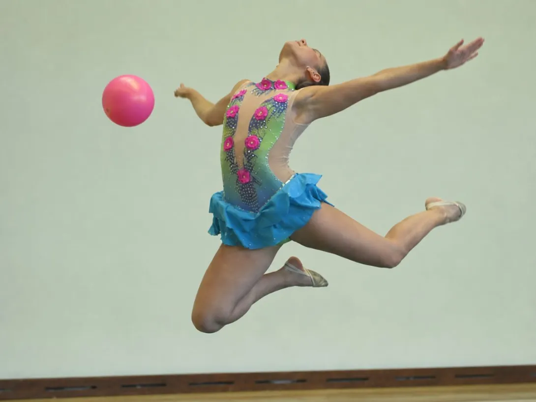 Gimnasta ejecutando un salto con pelota durante una presentación de Gimnasia Rítmica