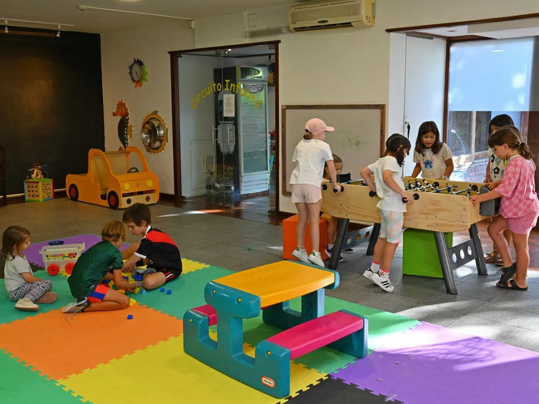 Niños jugando en el piso y al futbolito en el Club